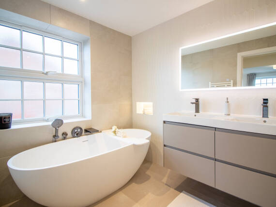 Salle de bains lumineuse avec baignoire en îlot et double plan de lavabo.