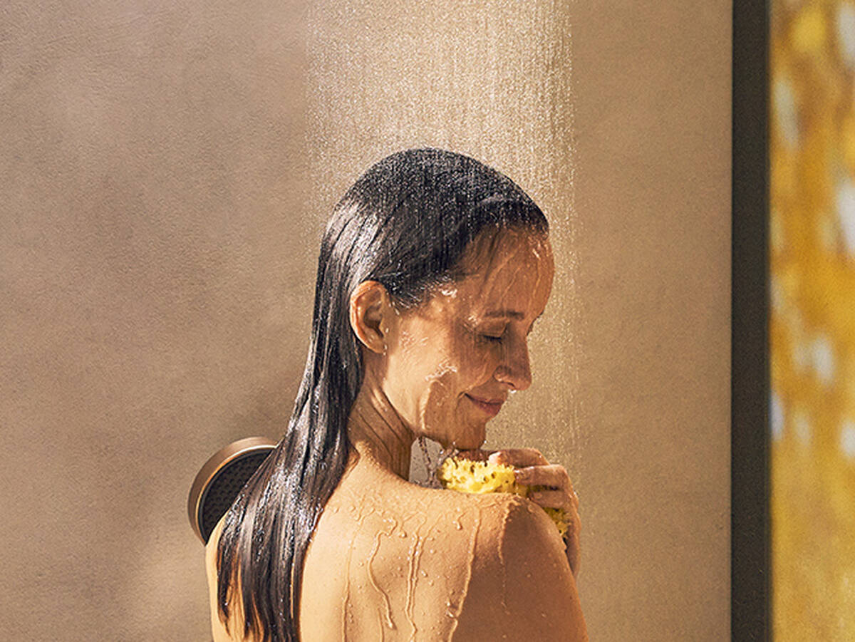 Femme se douchant sous une douche hansgrohe.