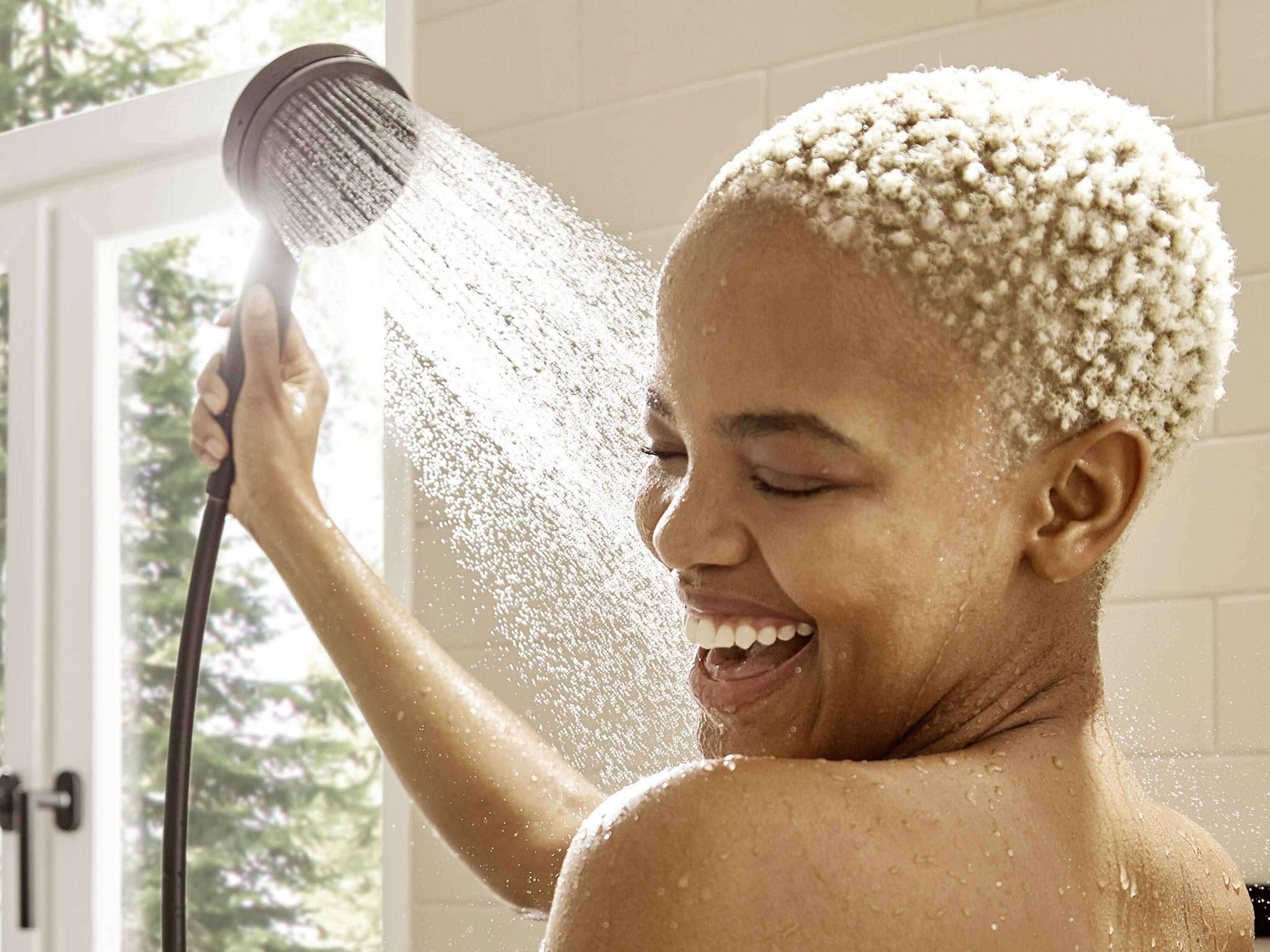 Laughing woman showers with Pulsify S hand shower.