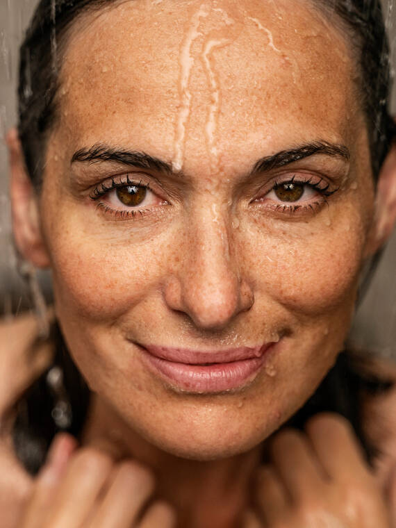 Vand løber over ansigtet på en kvinde i brusebadet