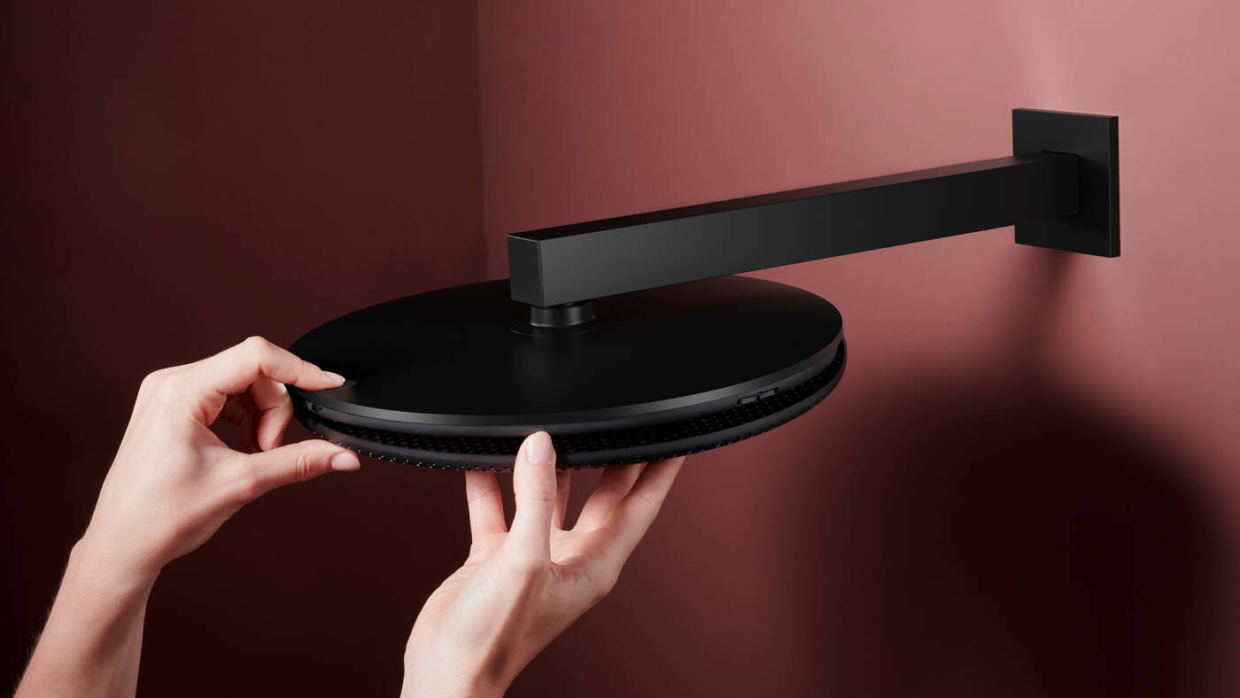 Hand removing the mesh cover on the Raindance Alive overhead shower.