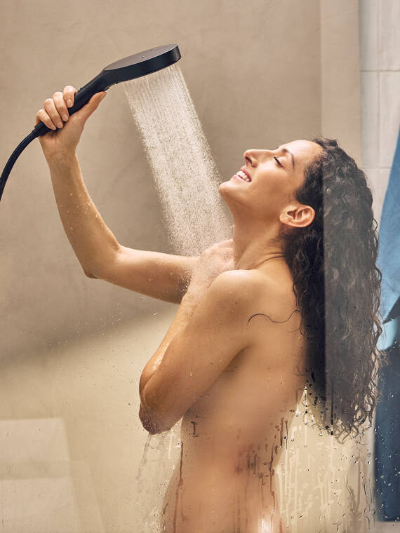 Frau duscht mit Handbrause.
