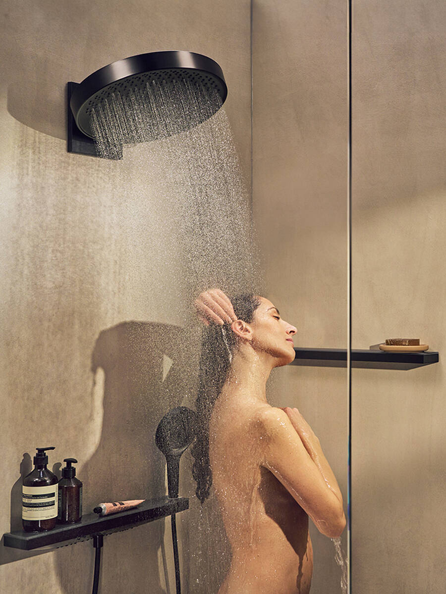 Frau duscht entspannt unter großer hansgrohe Regenbrause.