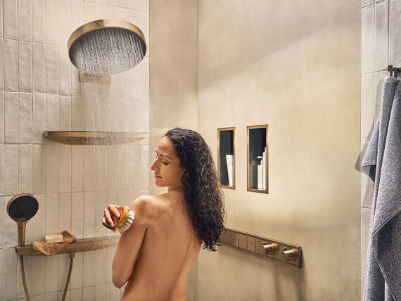 hansgrohe의 RainSelect 서모스탯으로 샤워하는 여성의 모습.