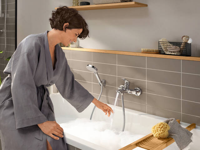 Woman at the bath tub with exposed installation bath tub faucet.