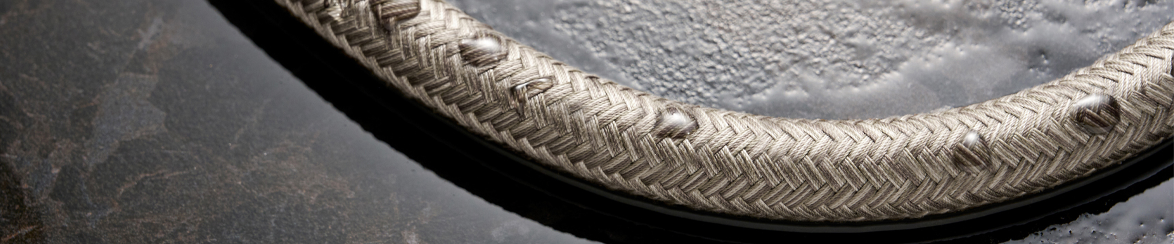 Geflochtener Metallschlauch von hansgrohe mit Wassertropfen auf der Oberfläche.