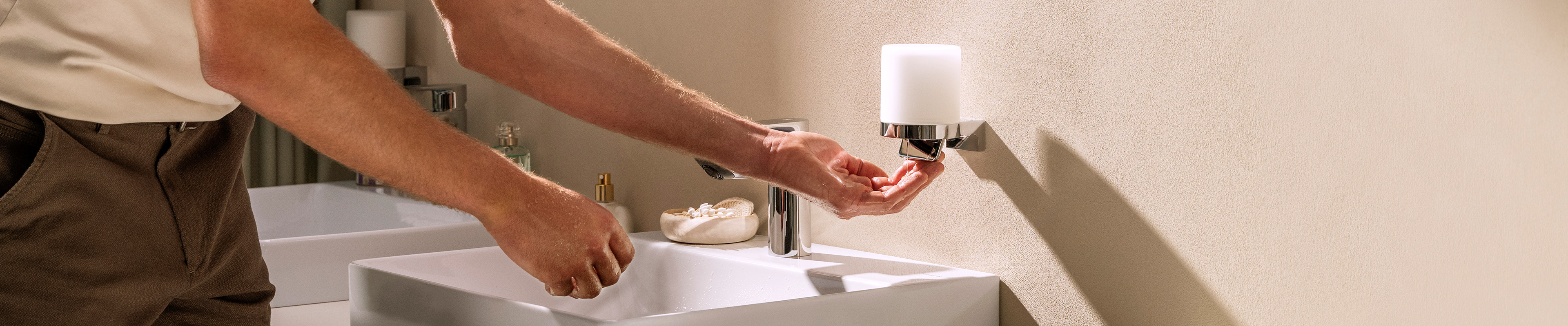 Man using the hansgrohe AddStoris S soap dispenser.