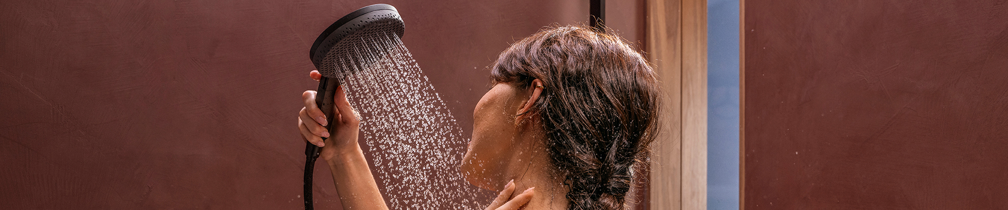 Kvinde tager brusebad med Raindance Alive håndbruser fra hansgrohe.