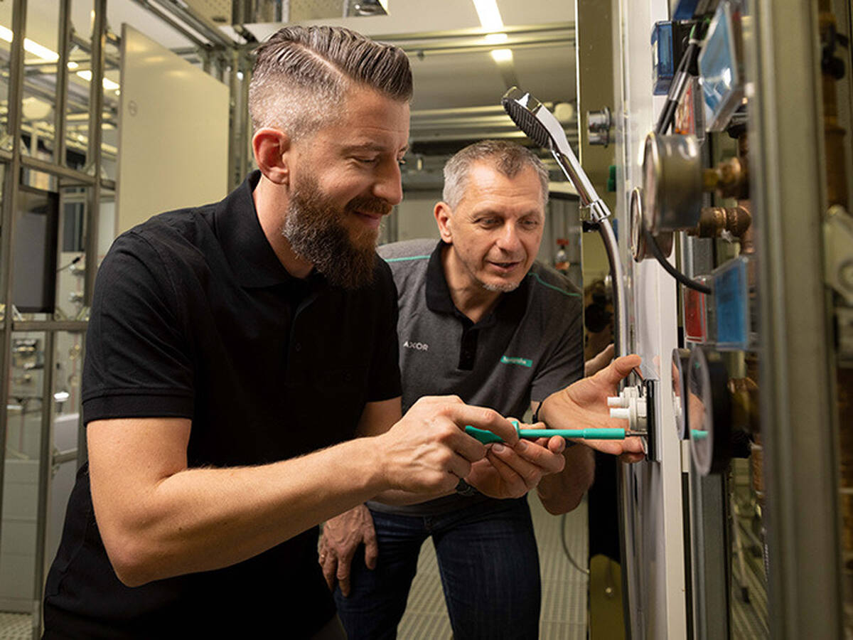 Two tradespeople installing a thermostat on the wall. 