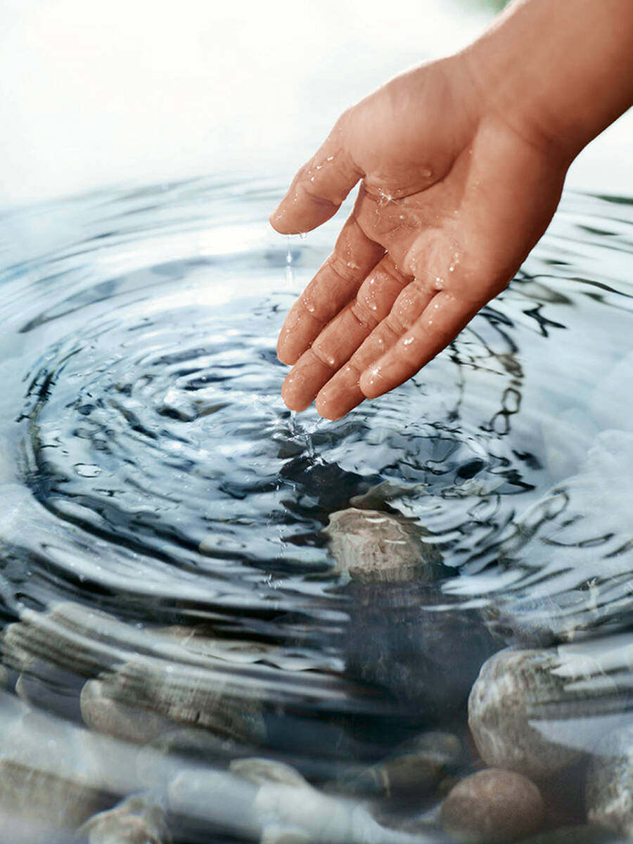 Eine Hand greift in einen See mit Wasserstrudel.