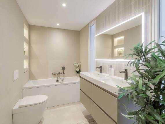 Salle de bains moderne et lumineuse avec baignoire douche et double plan de lavabo.