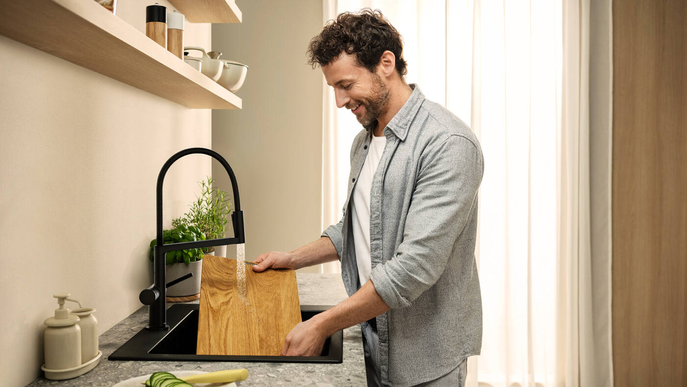 Een snijplank wordt onder de douchestraal gereinigd.