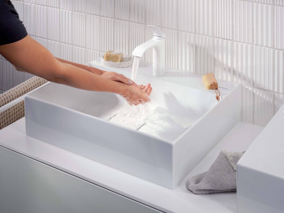 Une personne se lave les mains sous le mitigeur Vivenis de hansgrohe en blanc mat.
