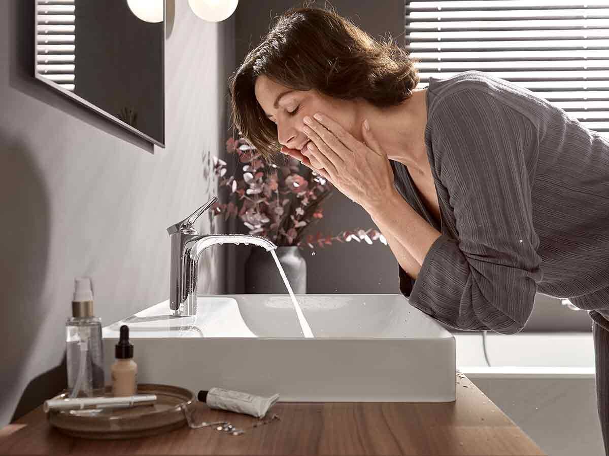 Frau am Waschtisch mit Vivenis Waschtischmischer.	