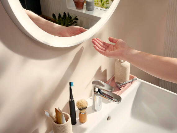 Main touchant un capteur sous un miroir hansgrohe Xarita Lite.