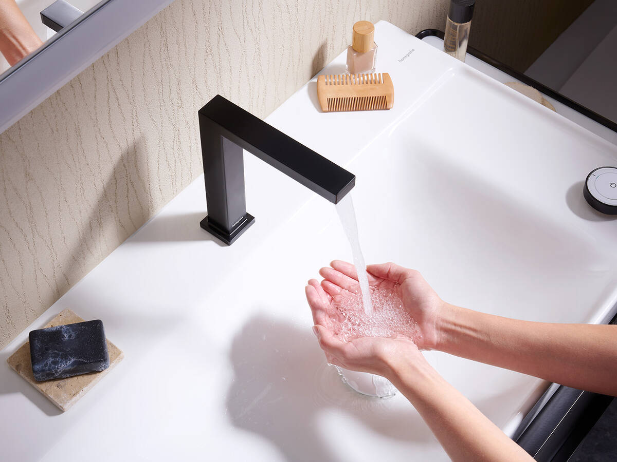 Hände unter mattschwarzer hansgrohe Tecturis E Armatur.