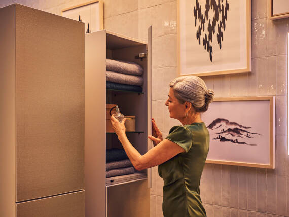 Femme rangeant des serviettes dans un meuble de salle de bains.
