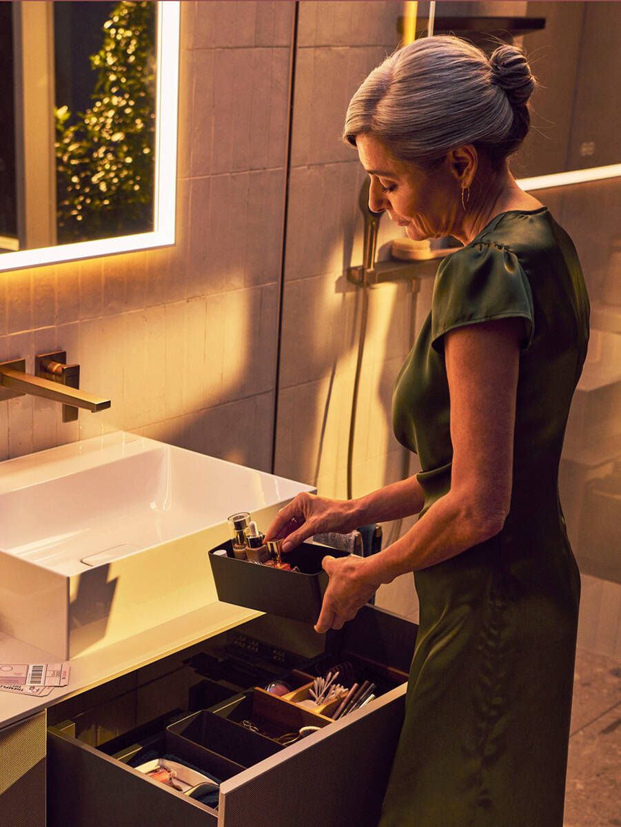 Frau sortiert Badutensilien in hansgrohe Waschtischschrank.
