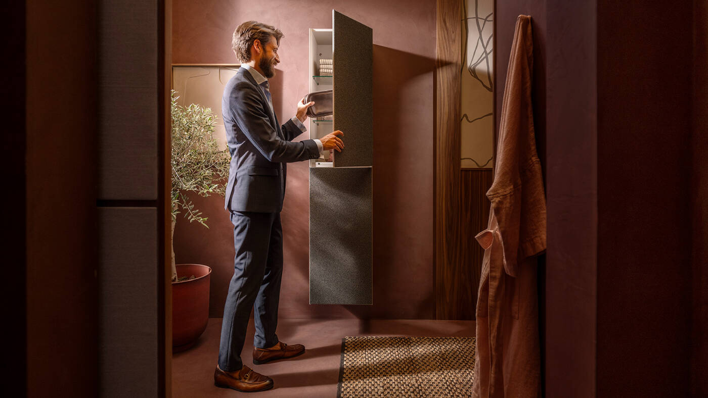 Mann an geöffnetem Xevolos E Hochschrank von hansgrohe.