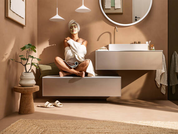 Žena sedí s prekríženými nohami na Sideboard hansgrohe.