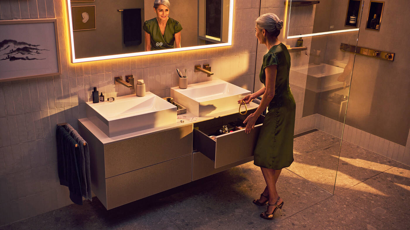 Frau an hansgrohe Xevolos E Waschplatz mit geöffneter Schublade am Waschtischunterschrank.