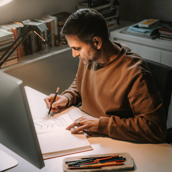 Designér studia PHOENIX při skicování nábytku.